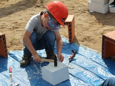 Junge mit Hammer in der Hand schlägt auf einen Stein