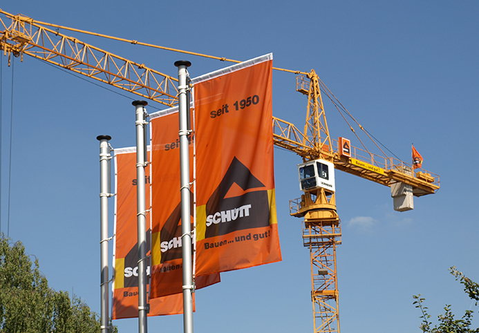 Fahnen mit dem Schütt Logo vor Kran